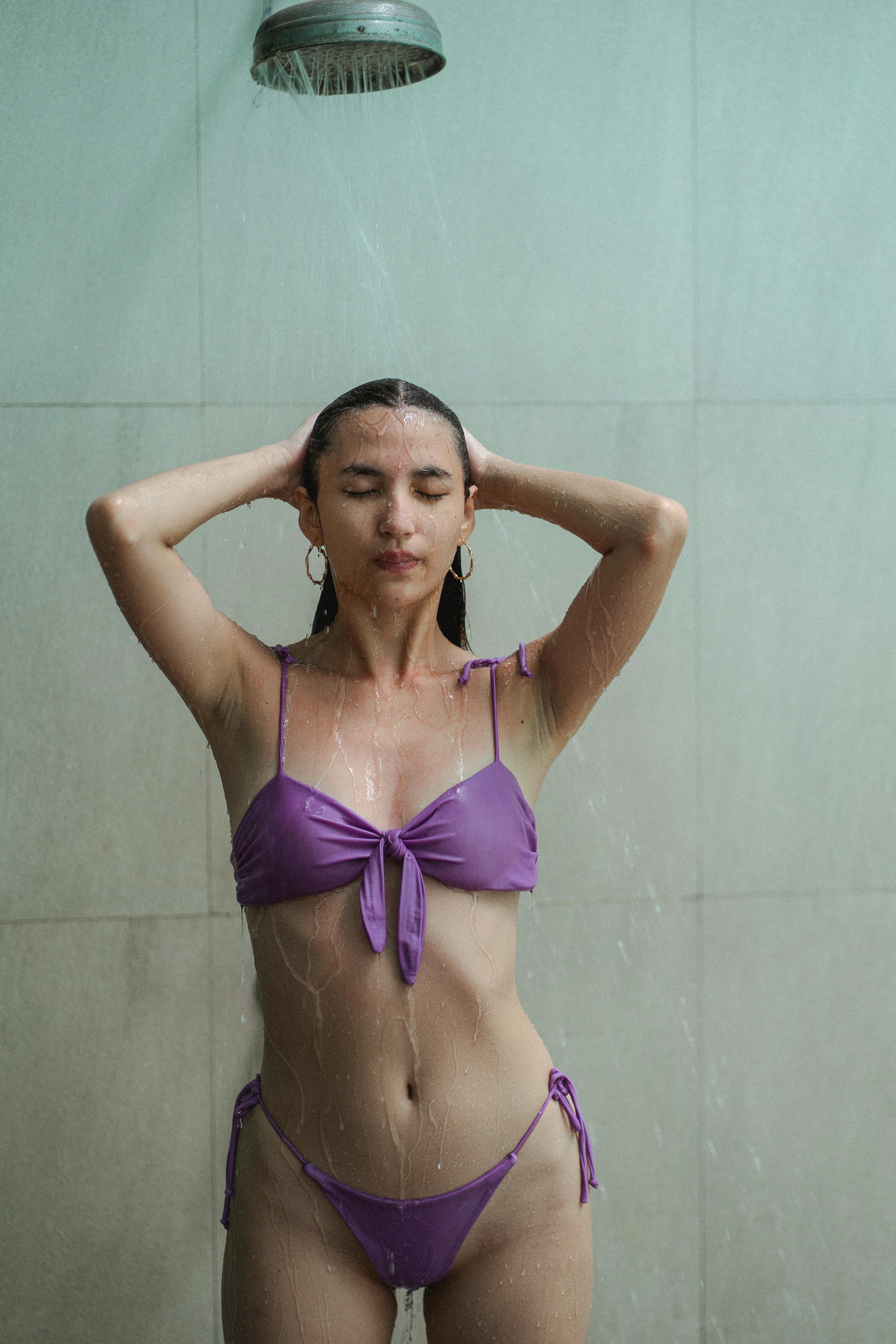slim sensual woman in violet bikini washing body in bathroom
