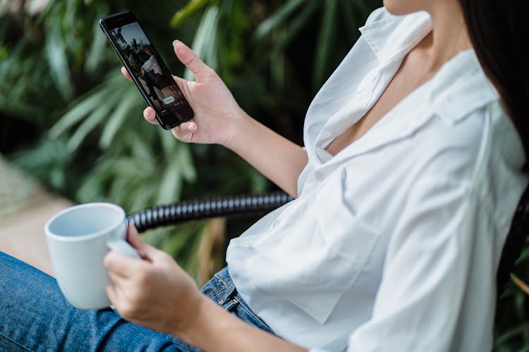 Crop Woman With Smartphone Sitting On Chair In Daylight