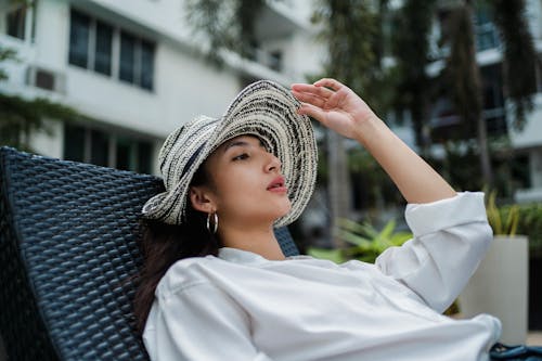 Stylish young ethnic woman recreating on lounger in hotel garden