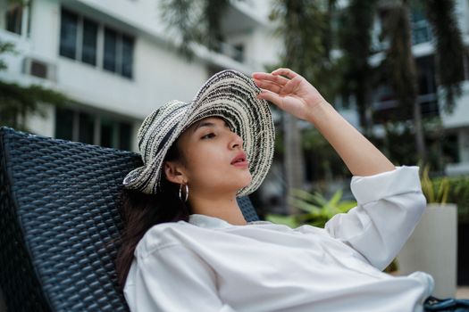 一位戴着别致草帽的女子正在热带度假胜地享受休闲时光