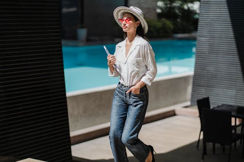 Fashionable young ethnic female walking near pool with laptop in hand