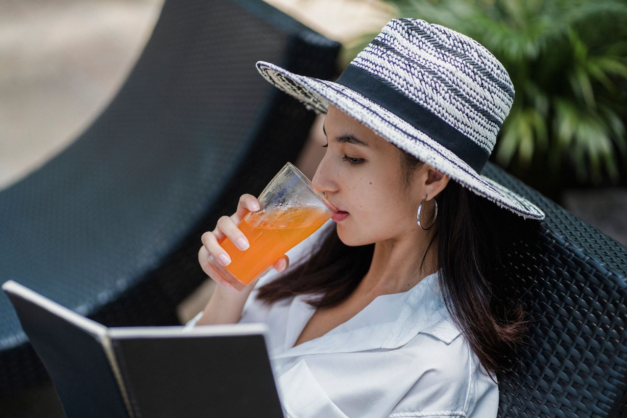 high angle of young asian lady in trendy straw hat and white shirt dri