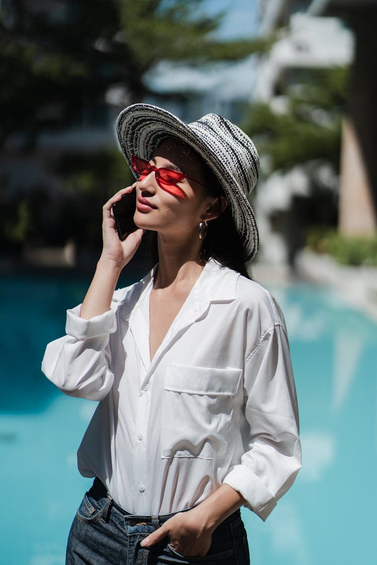 Content Young Asian Female Tourist Having Phone Conversation At Poolside