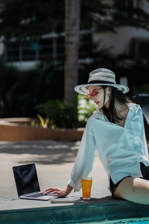 Self employed ethnic woman working on netbook near pool