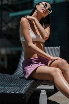 在度假村晒日光浴时，比基尼女子涂抹了防晒霜