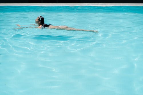 Young woman swimming in pool with transparent water