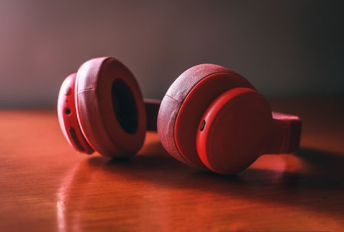 Free A pair of red wireless headphones placed on a wooden surface. Stock Photo