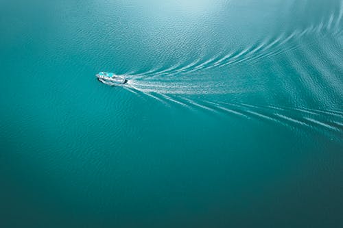 Free From above of modern boat sailing in blue rippling water in sunny day Stock Photo