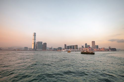 Free A stunning twilight view of Hong Kong's skyline with a ferry crossing Victoria Harbour, capturing the city's dynamic atmosphere. Stock Photo
