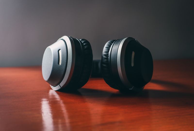 Black wireless headphones resting on a warm wooden surface