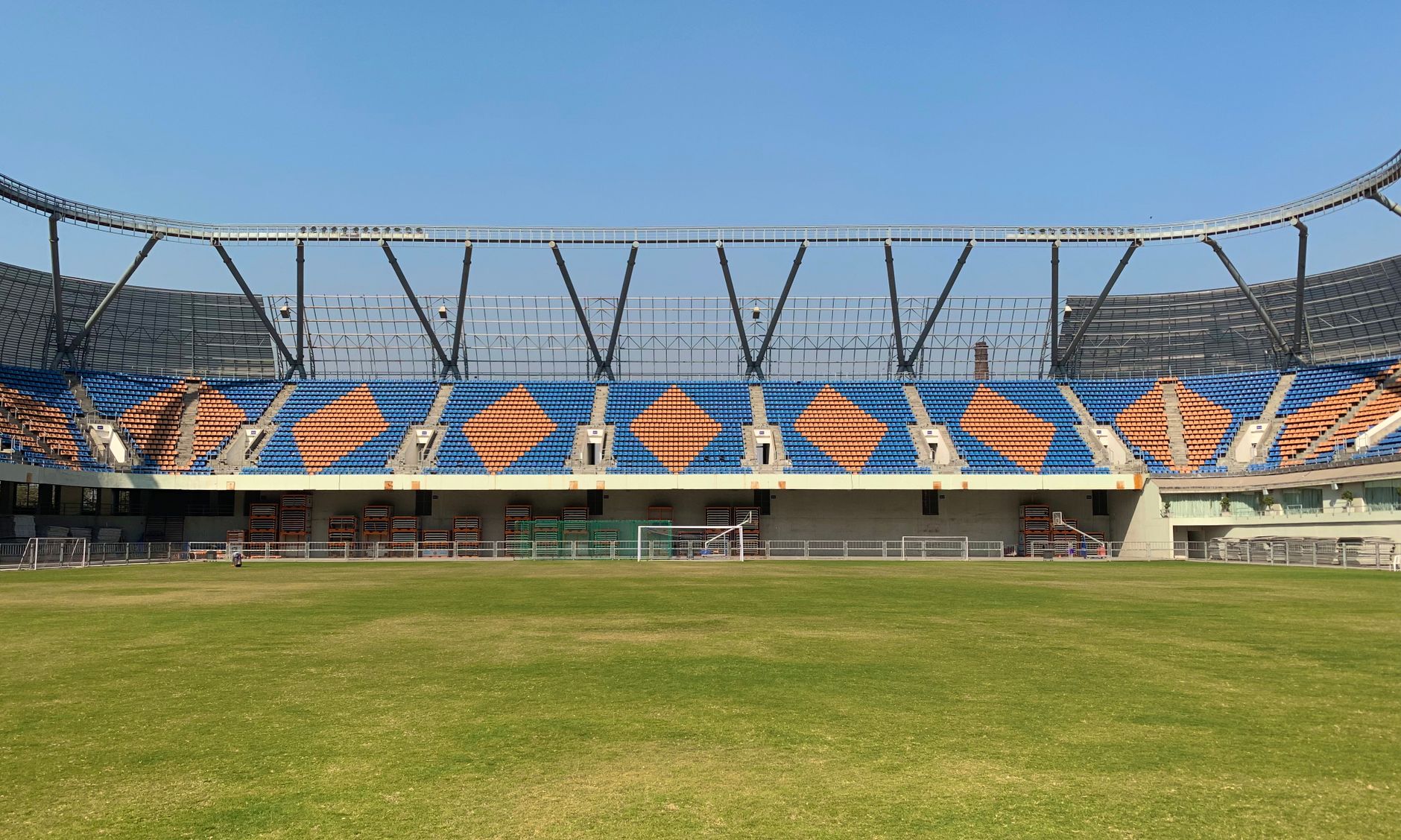 A wide view of an empty stadium in Ahmedabad, showcasing seating arrangements and green field.