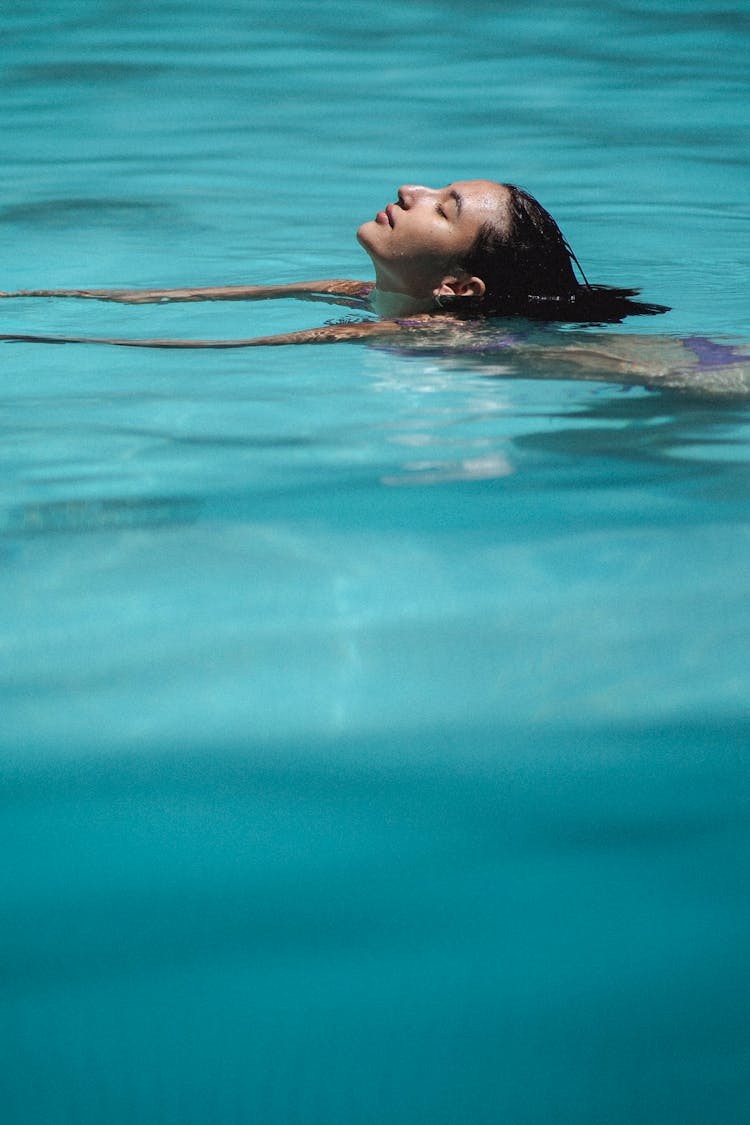 Young Asian Woman Swimming In Pool With Closed Eyes