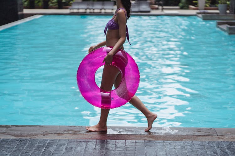 Unrecognizable Fit Woman With Lifesaver In Hand Walking At Poolside