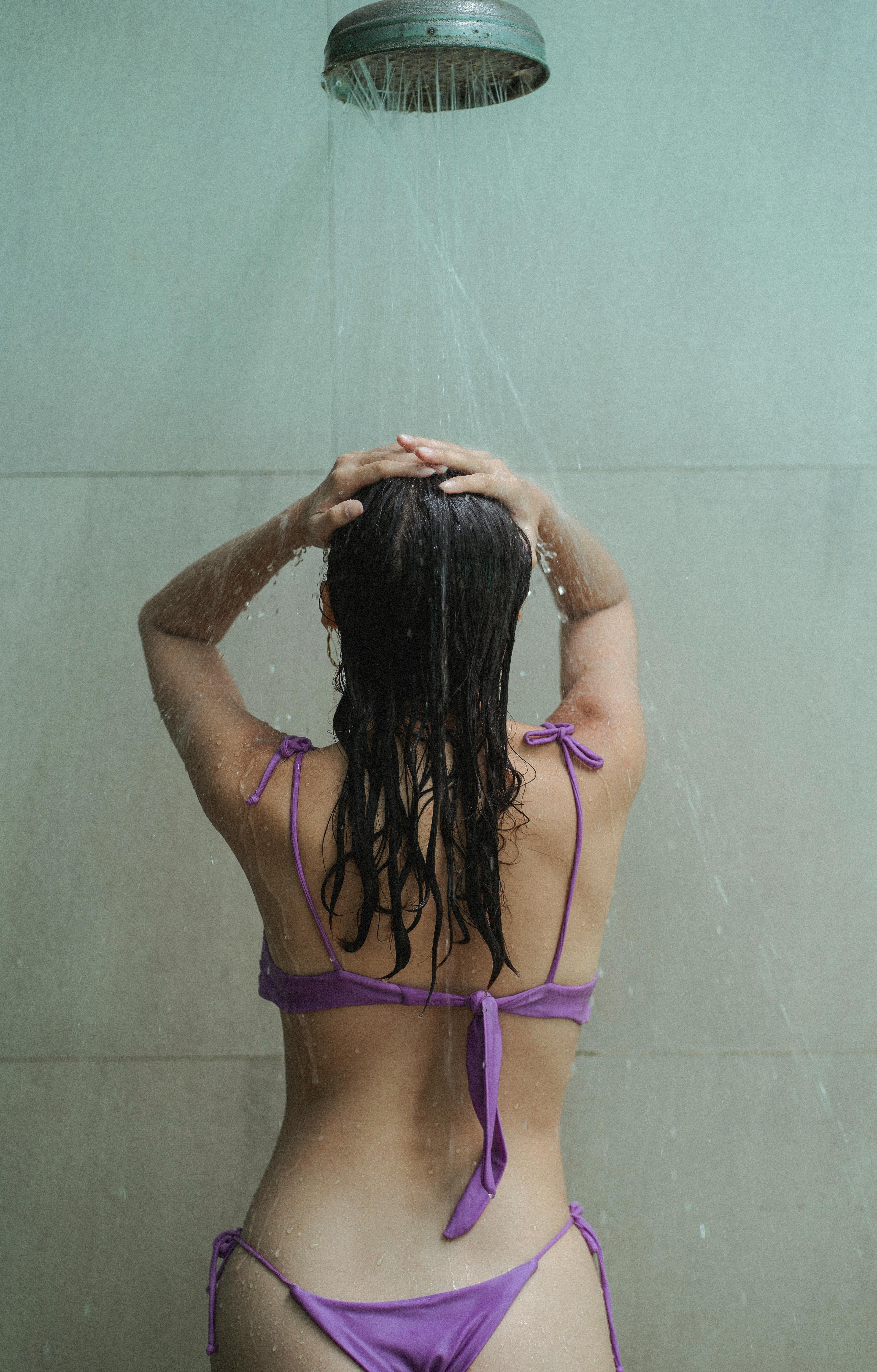 Faceless young fit lady taking shower in bathroom · Free Stock Photo