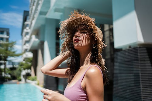 Dreamy young Asian lady recreating at poolside with closed eyes