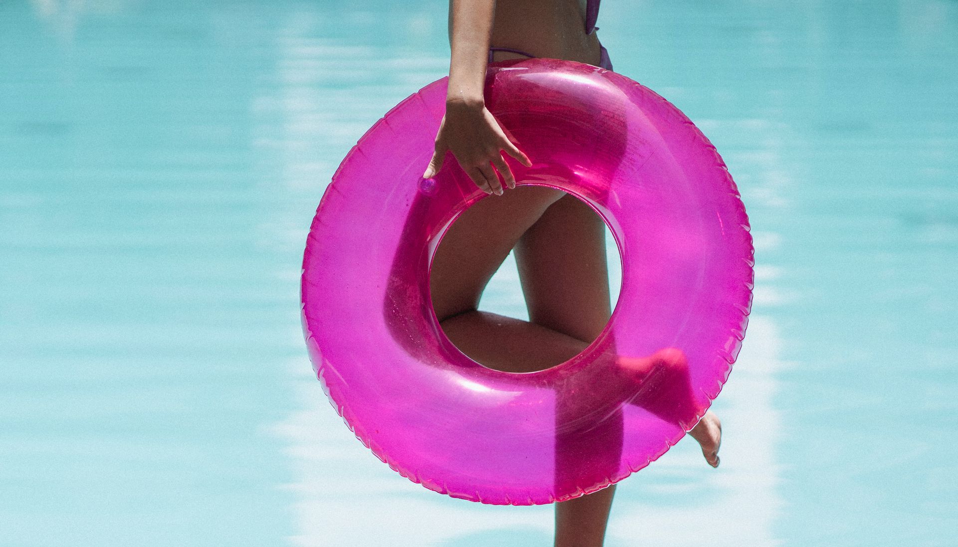 Unrecognizable slender woman with inflatable tube relaxing near pool
