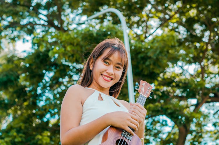 Cheerful Asian Woman With Ukulele On Street