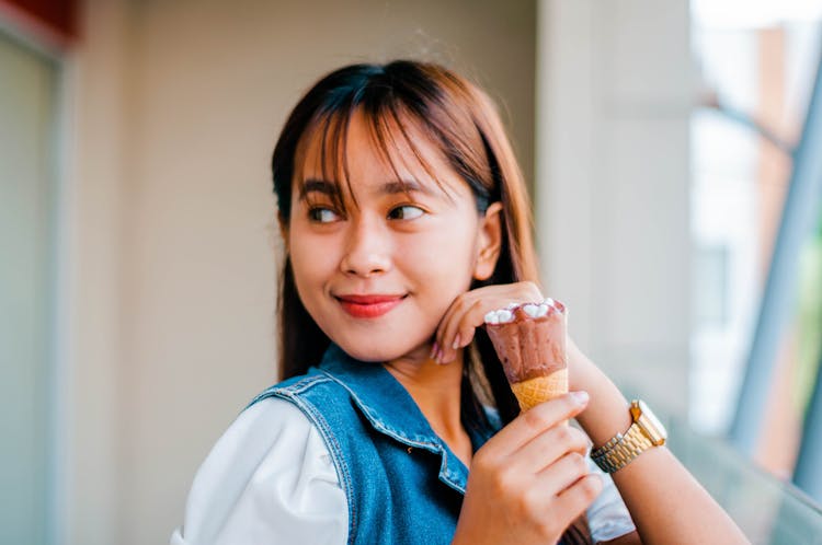 Content Asian Woman With Ice Cream On Balcony