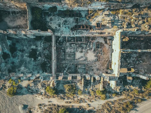 Drone view of ruined stone buildings with damaged walls and roofs located in uninhabited district