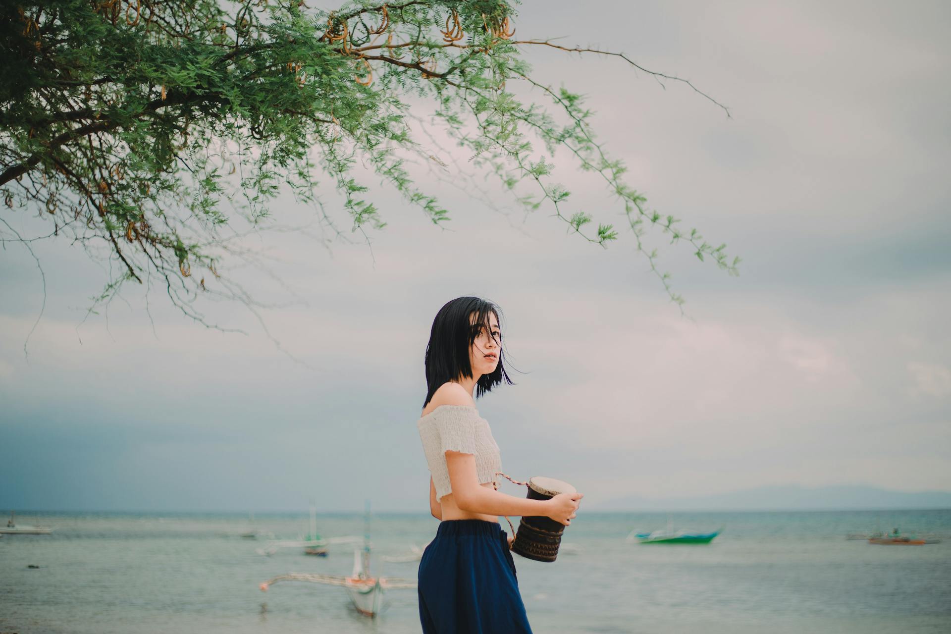 Young Asian woman on a peaceful Philippine beach, holding a basket.