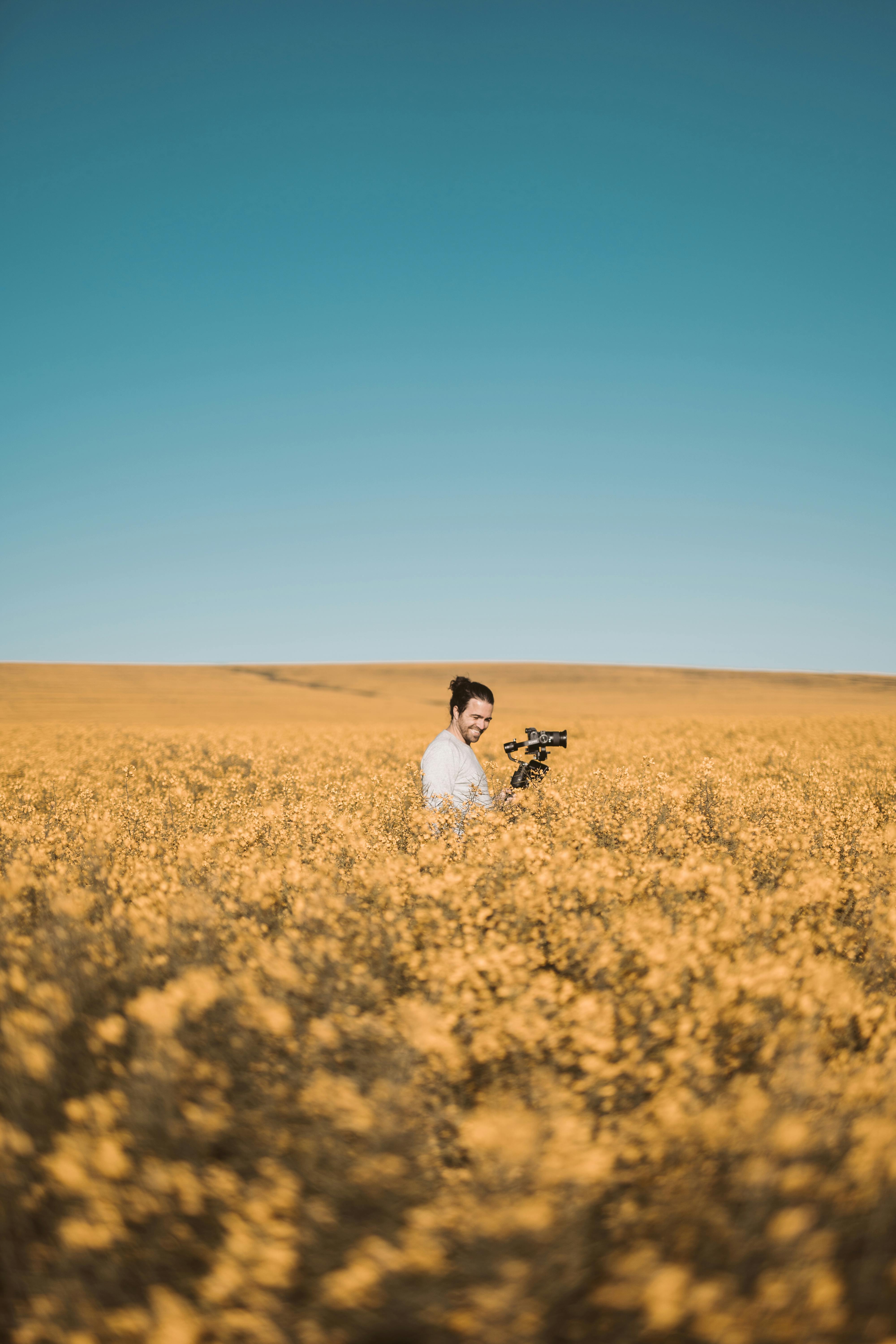 在南非开普敦，一名男子在晴朗的蓝天下，捕捉花田盛开的美丽