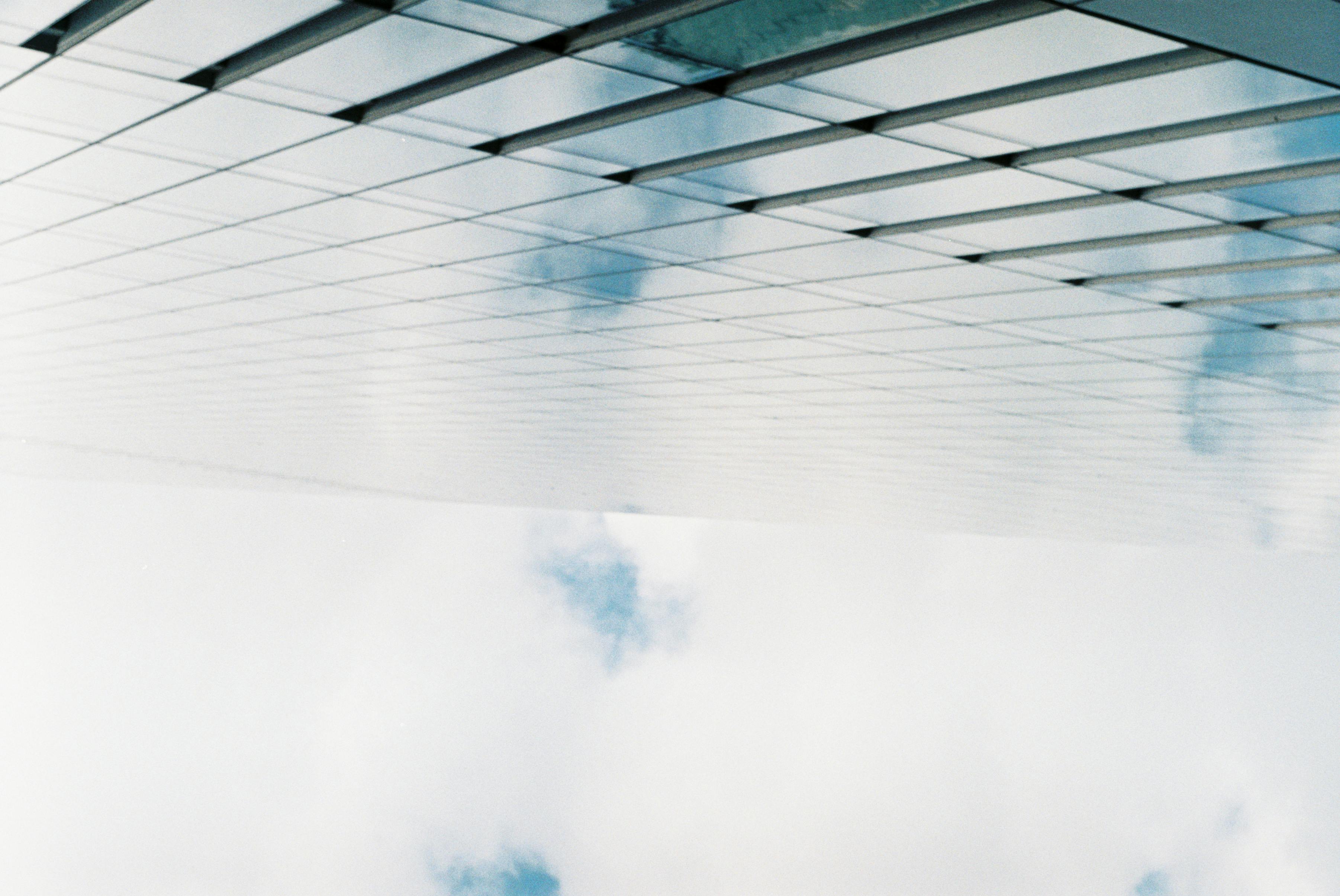 A low-angle shot of a modern glass building reflecting the sky, showcasing minimalist architecture.