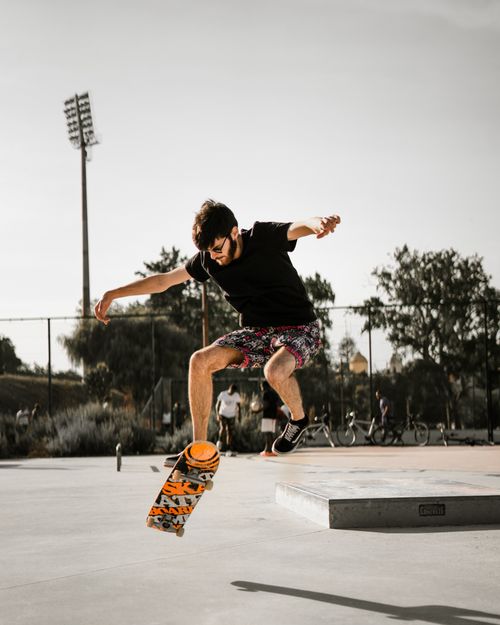 Free A skateboarder performs a trick mid-air at a skate park under a warm sunset in Aveiro, Portugal. Stock Photo