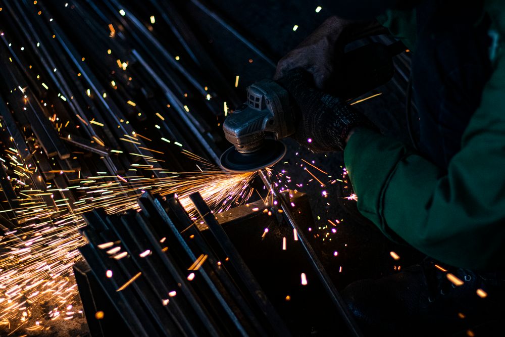 Worker grinding steel bars with flying sparks