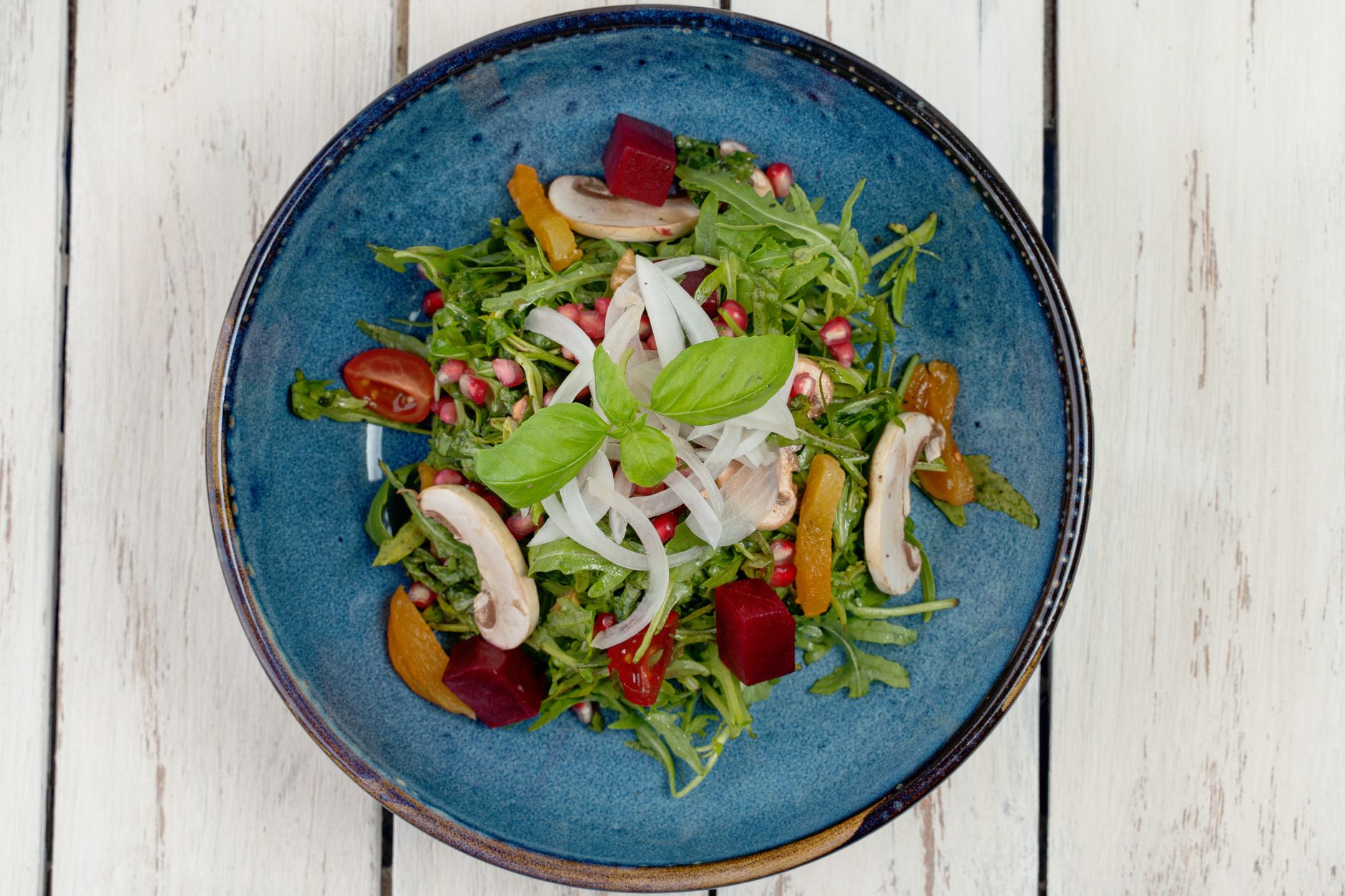 Close-up of pomegranate seeds and arugula leaves in salad bowl