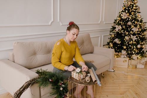 A Woman in Yellow Long Sleeves Wrapping a Gift