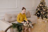 一位穿着黄色毛衣的女人，在节日树背景的舒适圣诞氛围中包装礼物
