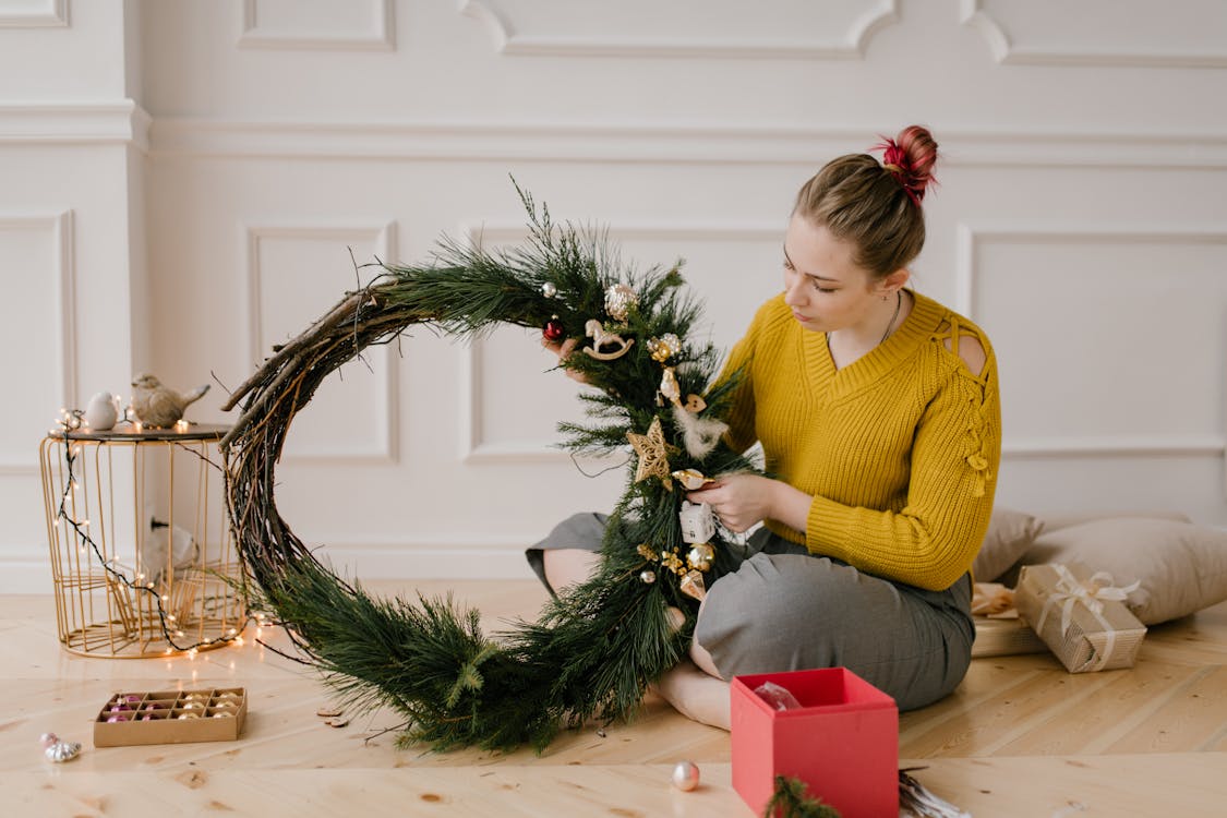 Fille En Pull Jaune Assis à Côté De L'arbre De Noël Vert