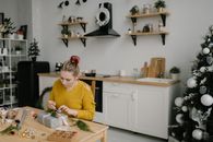 一名妇女坐在厨房里，用节日装饰品包装圣诞礼物