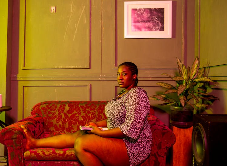 Thoughtful Sad Black Woman Sitting On Couch With Book