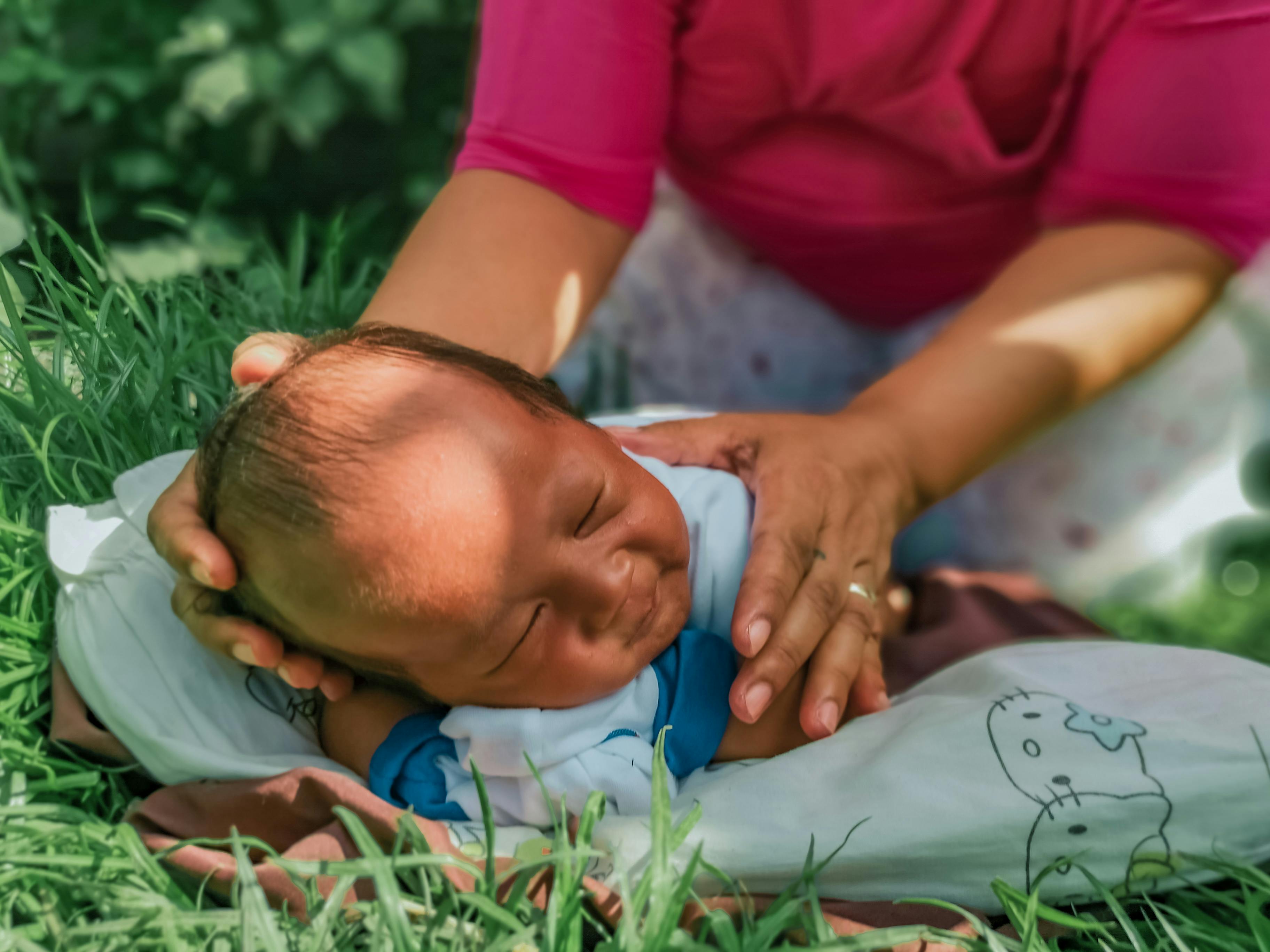 草地上，一个安静的婴儿正由一位女人温柔地照顾着