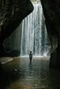 Back view of anonymous lady with arms outstretched enjoying freedom near waterfall in ravine in daylight