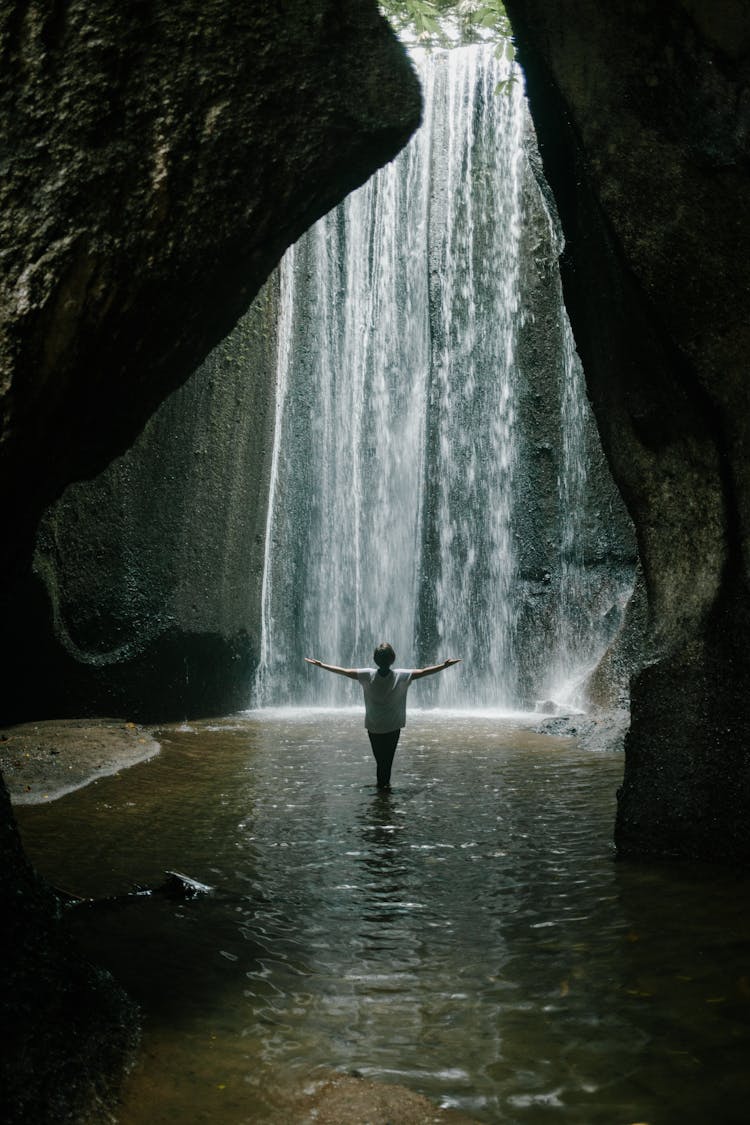 Unrecognizable Woman Standing In Gorge With Waterfall