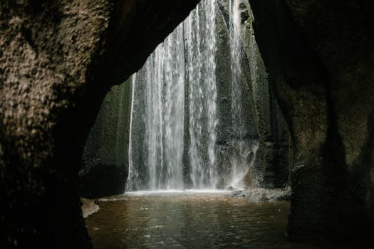 A stunning view of a waterfall cascading through a rocky cave in Bali, Indonesia.