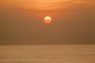 日落时分，明亮的橙色阳光在平静无垠的海面上映照着天空