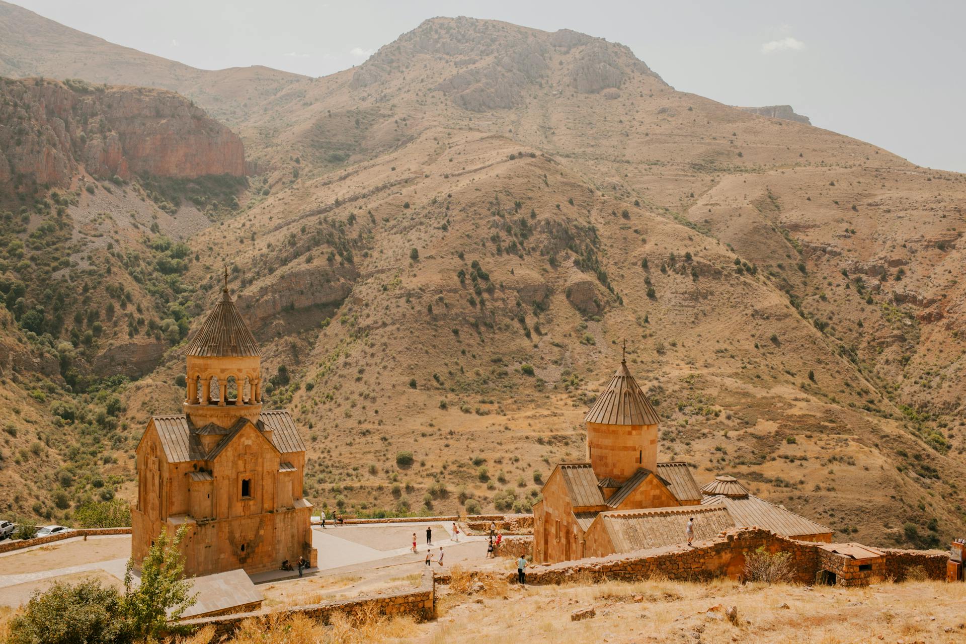 From above of travelers walking near old cathedrals located in mountainous area in sunny day