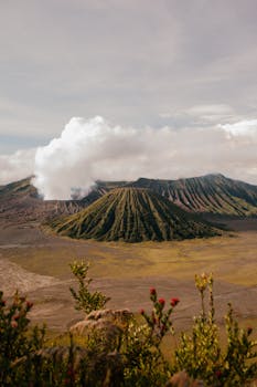 From above of rough rocky steaming volcanic highland area located in vast terrain under cloudy sky
