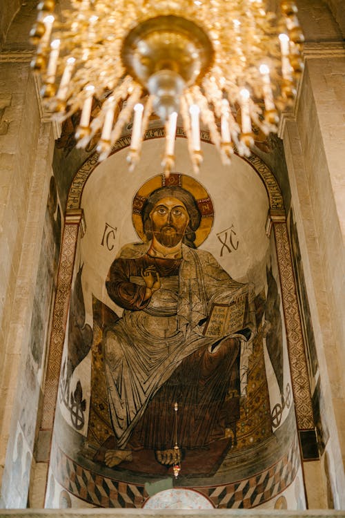 From below of painting of Jesus Christ on stone wall under chandelier in Christian cathedral