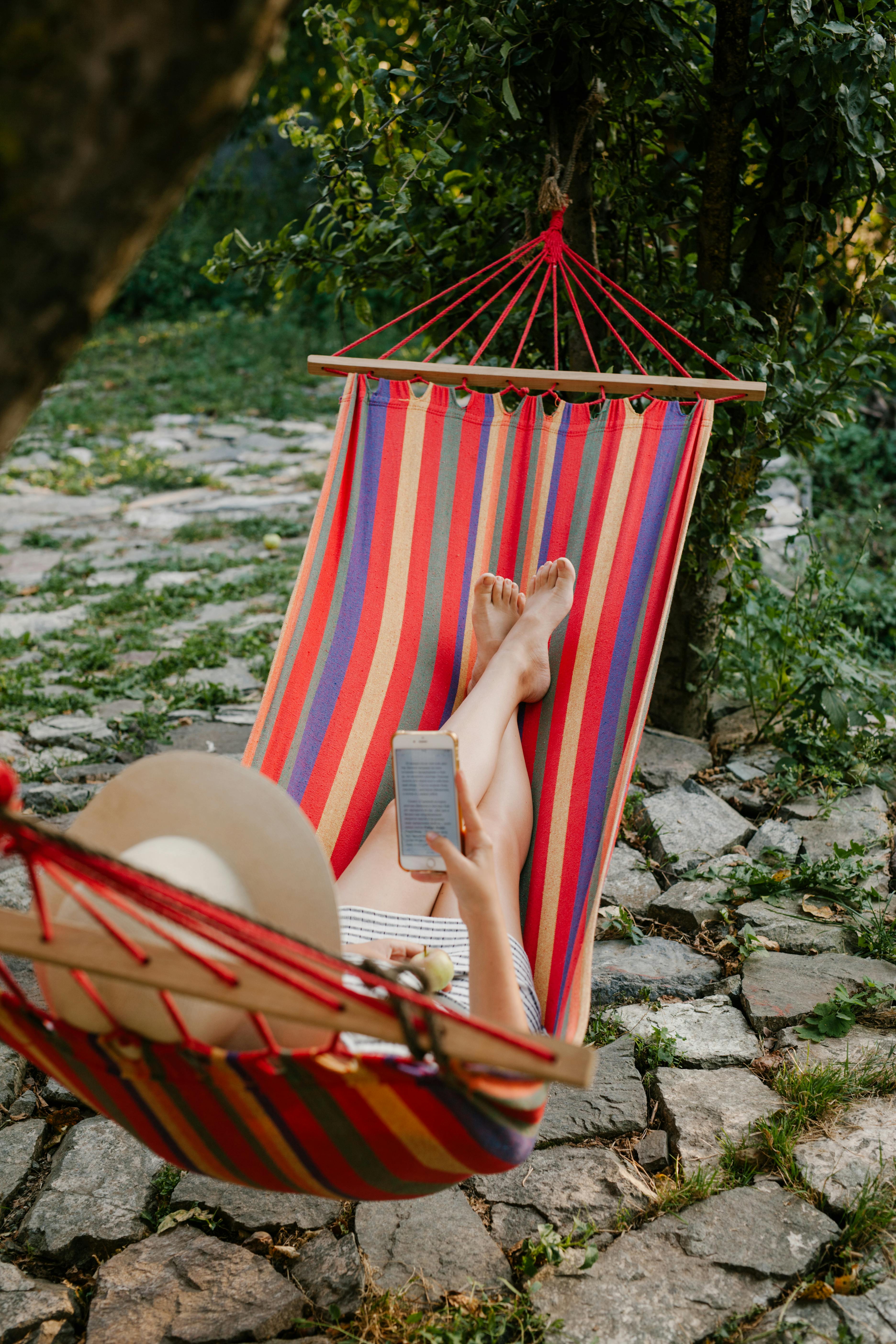 woman relaxing in hammock and browsing smartphone