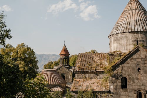 Aged stone building of cathedral with shabby walls and moss on tiled roof in old village