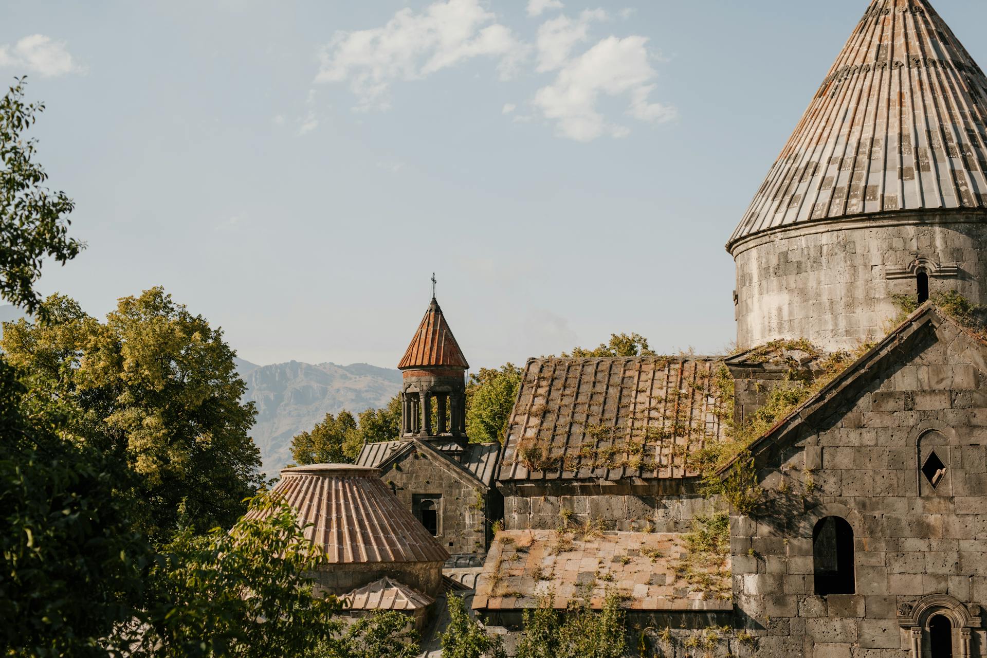 Aged stone building of cathedral with shabby walls and moss on tiled roof in old village