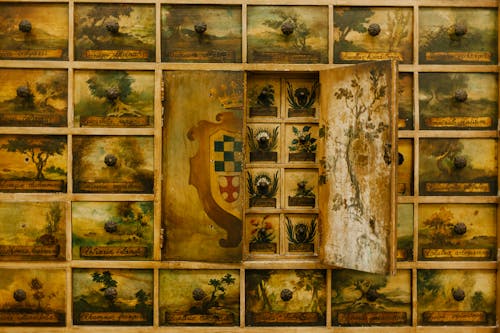 Wall with different paintings on cabinet doors with coat of arms in historical style