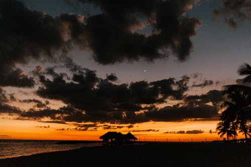 Hut with straw roof under clouds at sunset