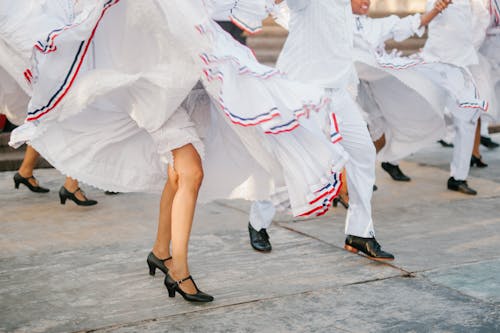 Free Crop unrecognizable artists in white costumes dancing on street during festival on sunny day Stock Photo
