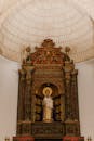 Majestic masonry altar with ornamental columns and statue of Virgin under geometric cupola in aged cathedral