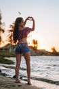 Woman in Red and White Checked Shirt and Blue Denim Shorts Standing on Beach Shore during